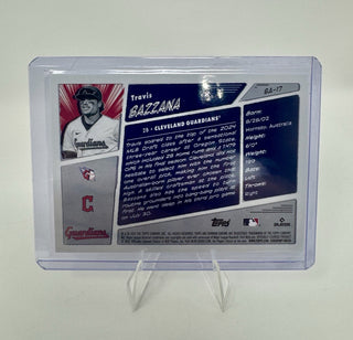 A collectible baseball trading card featuring Travis Gazzara, displayed inside a clear protective plastic case on a small clear stand against a light gray background.